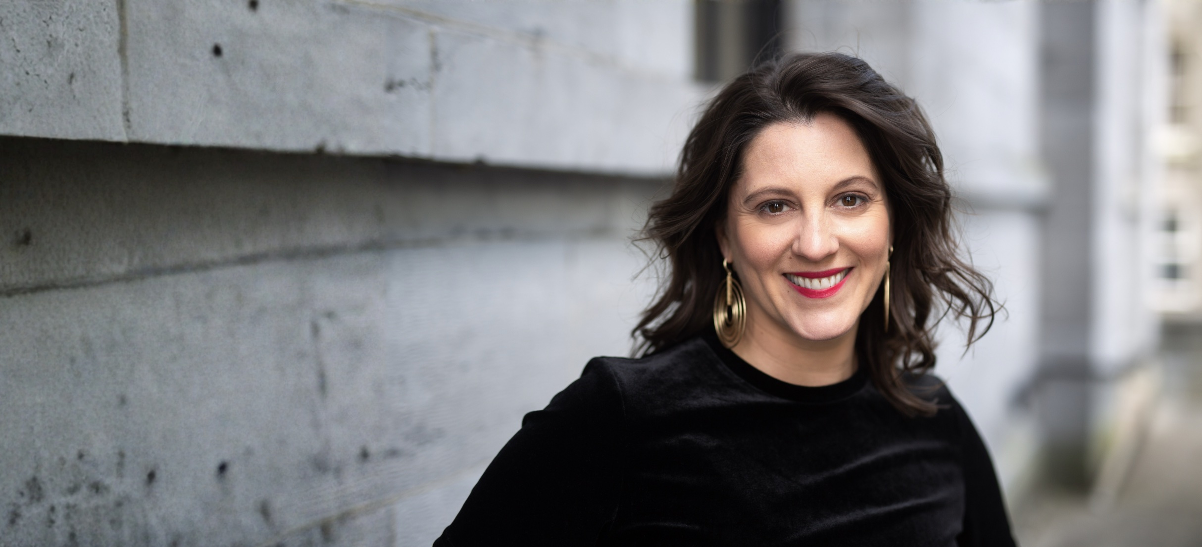 Carly Clark Zimmer smiling beside a stone wall